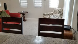A dining area with a granite table, two wooden chairs, a red sofa, a floral armchair, and a small round table with a lamp. - New Kingston Guest Apartment at Eight (Kingston)