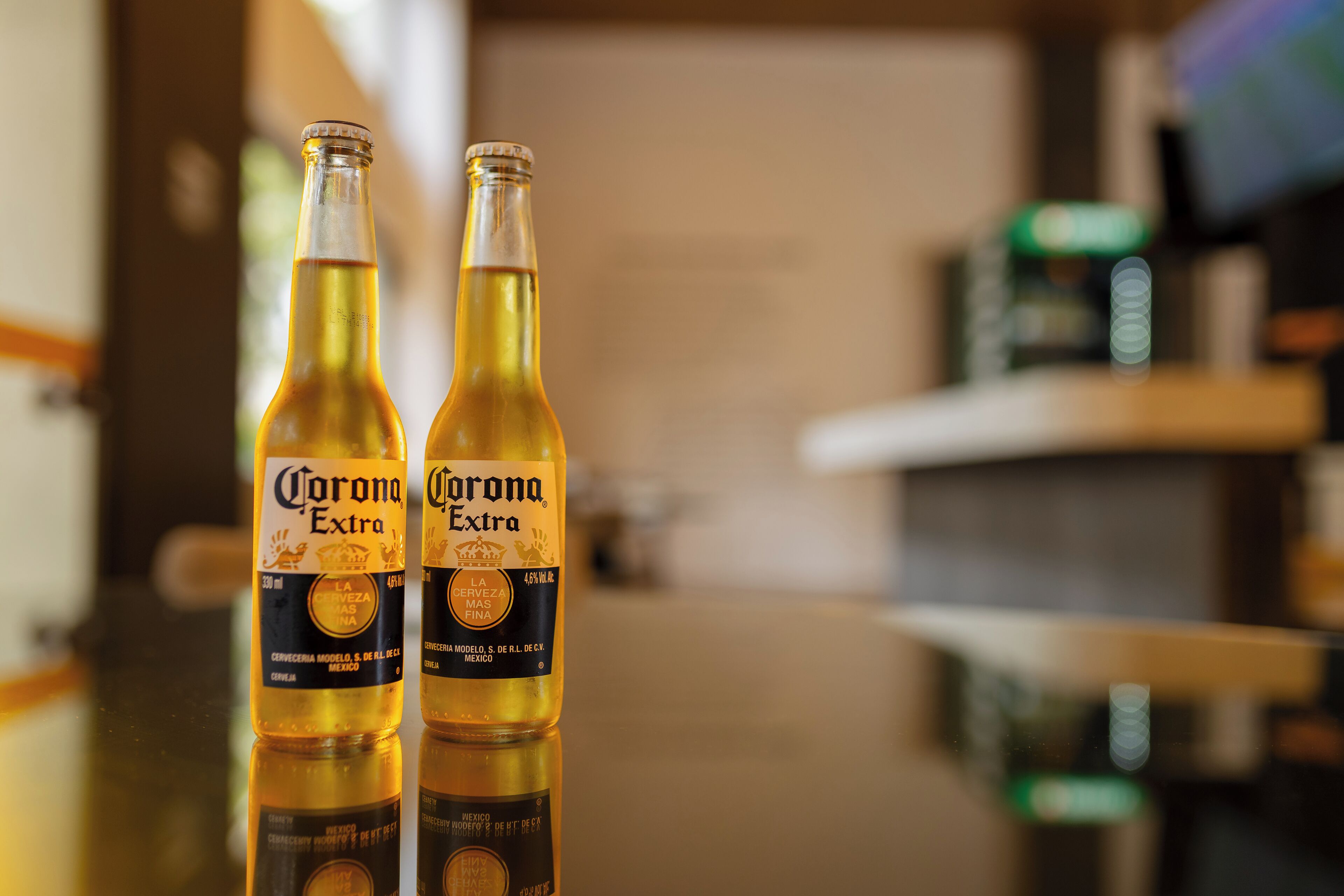 Deux bouteilles de bière Corona Extra posées sur une surface réfléchissante.