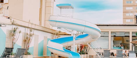 Una piscina techada, una piscina al aire libre, sombrillas