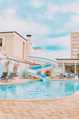 Una piscina techada, una piscina al aire libre, sombrillas