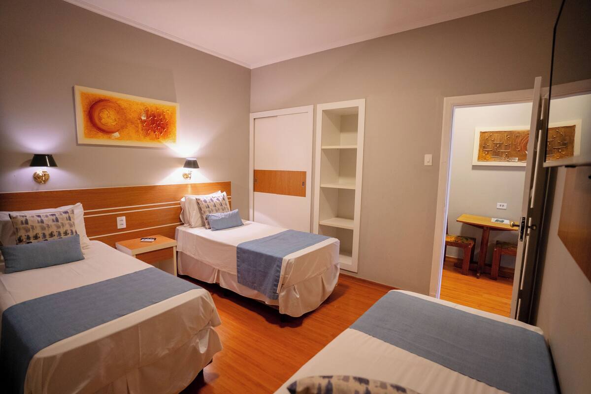 Ein Hotelzimmer mit zwei Betten, einem Schreibtisch und einem Kleiderschrank.