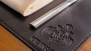 A table setting with a folded napkin, a knife, and a fork on a black leather placemat with embossed text.
