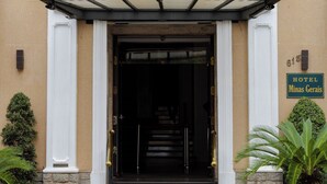 Een hotelentree met een klassiek gevelontwerp, een trap die naar de deur leidt, en een bord met de naam van het hotel.