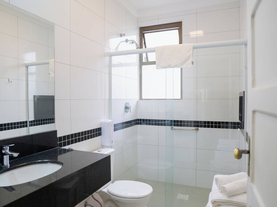 A modern bathroom with a black countertop sink, white toilet, and a glass shower enclosure.