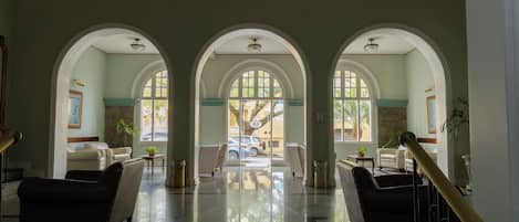 A lobby with three arched doorways, a staircase, and a view of the street outside.