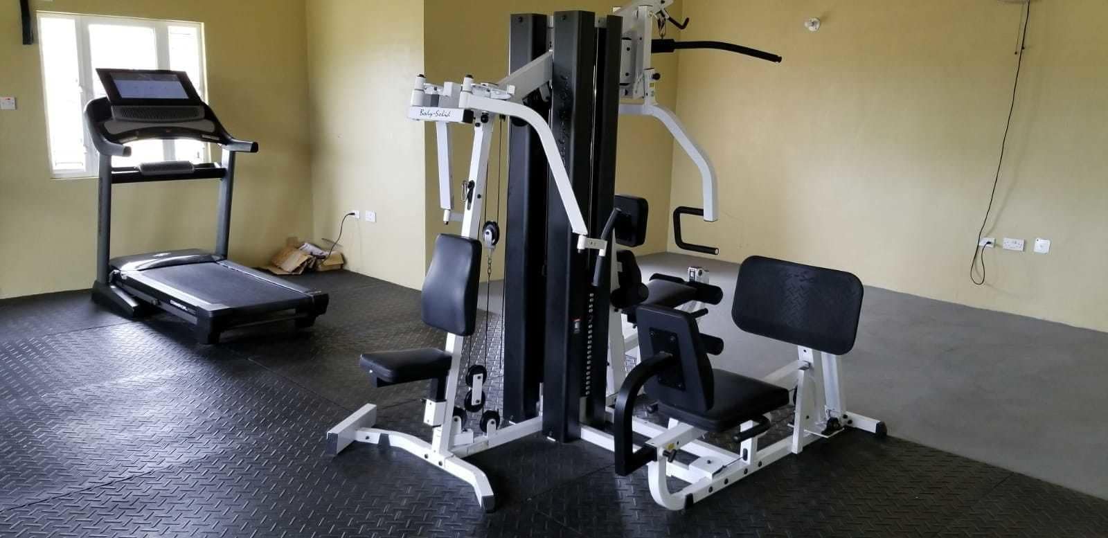 A gym with a treadmill, weight machines, and a bench.