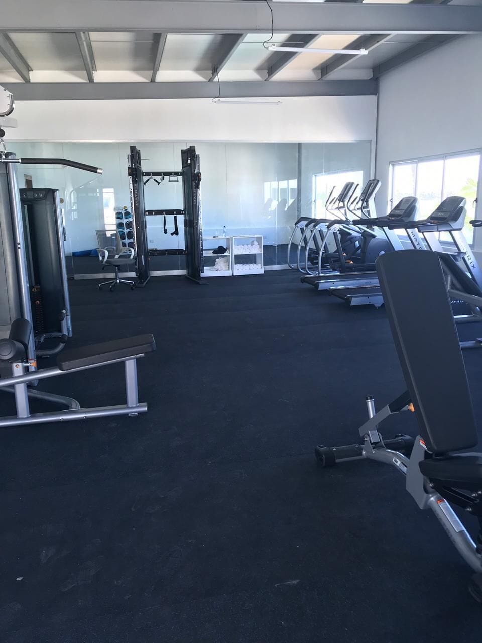 A gym with cardio machines, weightlifting equipment, and a mirrored wall.