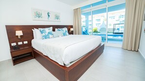 Una cama grande con cabecera de madera, una mesita de noche con lámpara y una obra de arte en la pared.