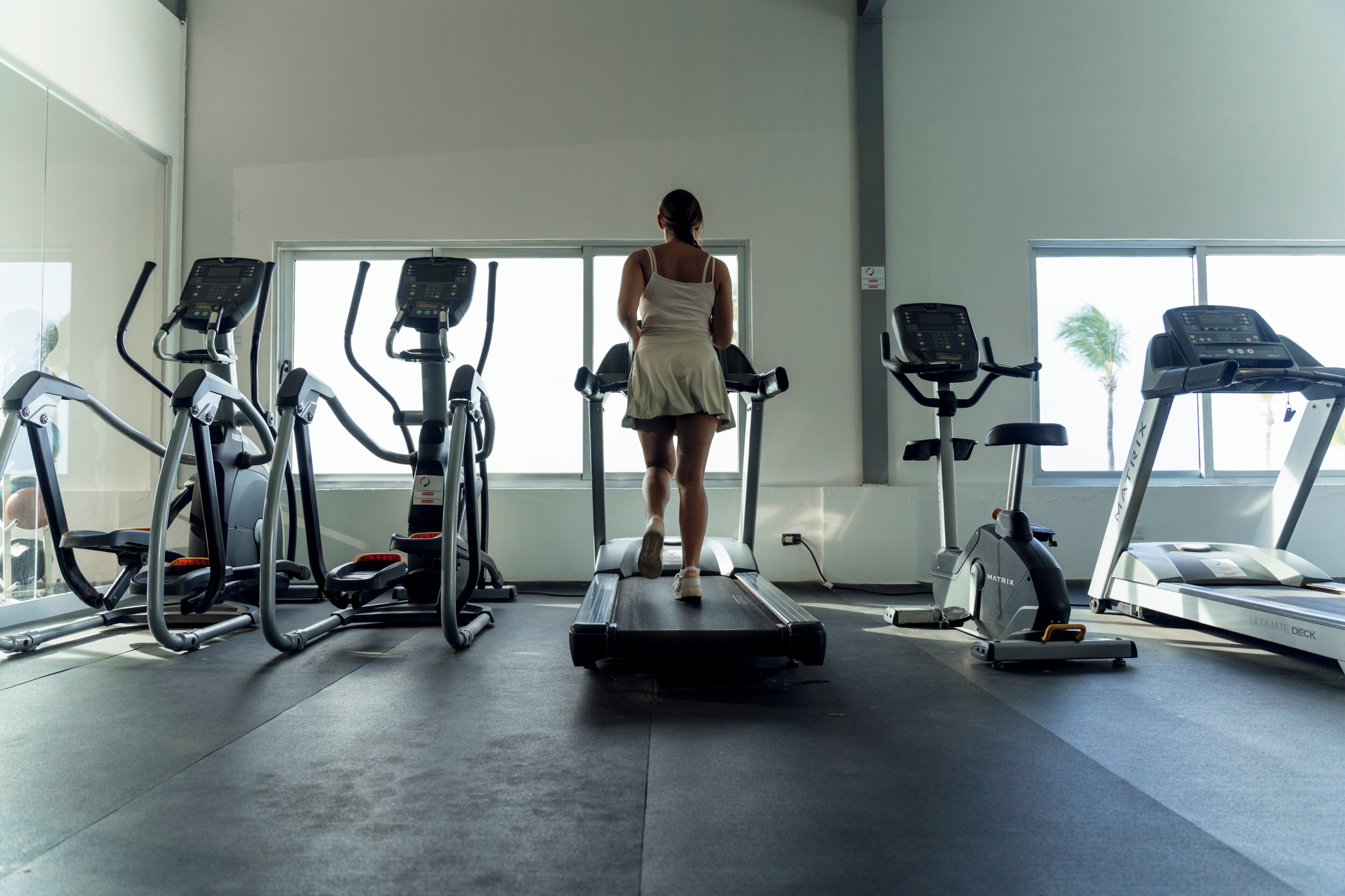 A gym with treadmills, ellipticals, and a mirrored wall.