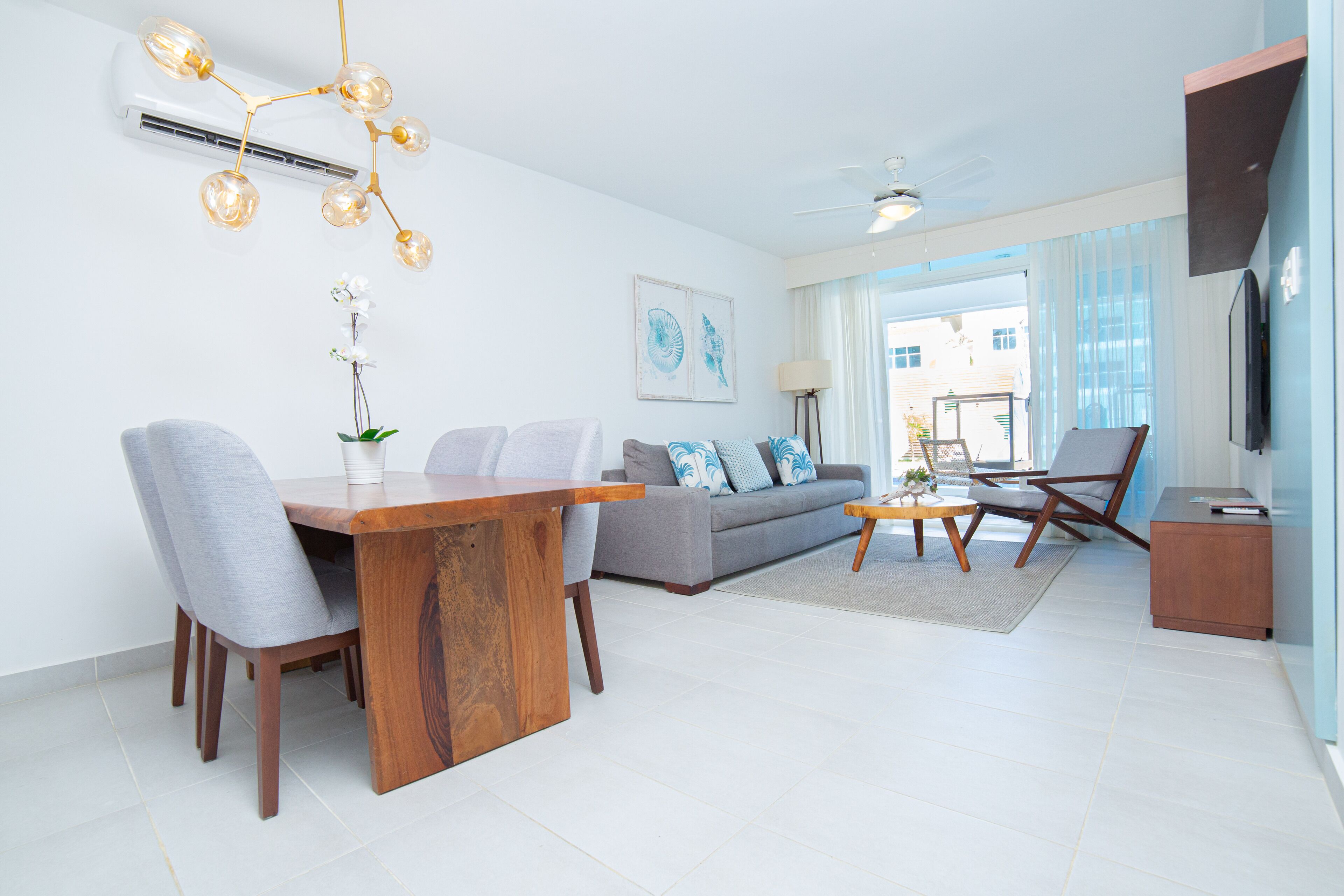 A modern living room with a dining area, a sofa set, a coffee table, and a TV.