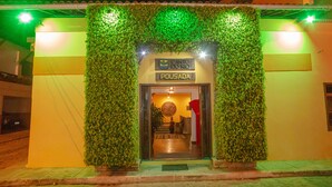 Entrada de un hotel con un arco de follaje verde, un letrero que dice "Canto do Rio Pousada" y una recepción visible.
