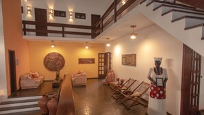 Amplia sala de estar con techo alto, una escalera y una estatua.