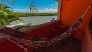 Una hamaca en un balcón con vista a un río, donde se ve el agua y la vegetación.