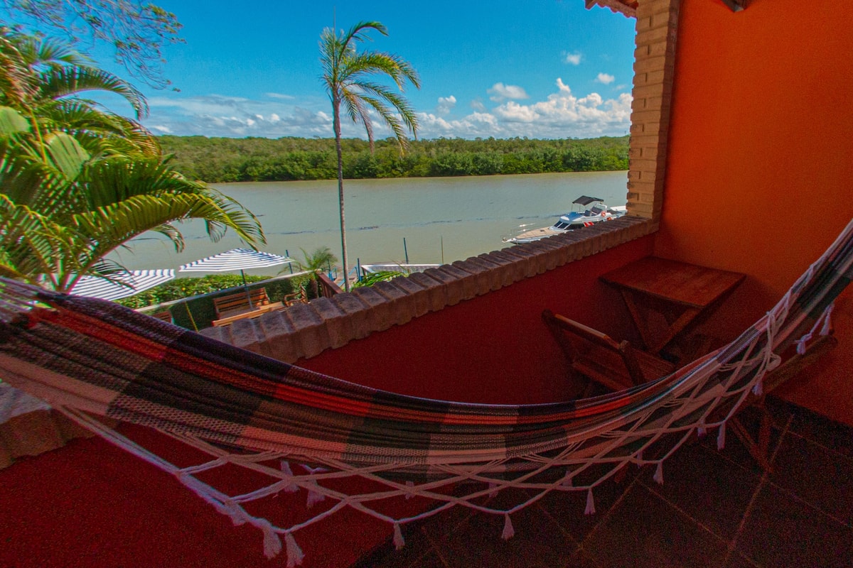 Eine Hängematte auf einem Balkon mit Blick auf einen Fluss, mit Ausblick auf Wasser und Grün.