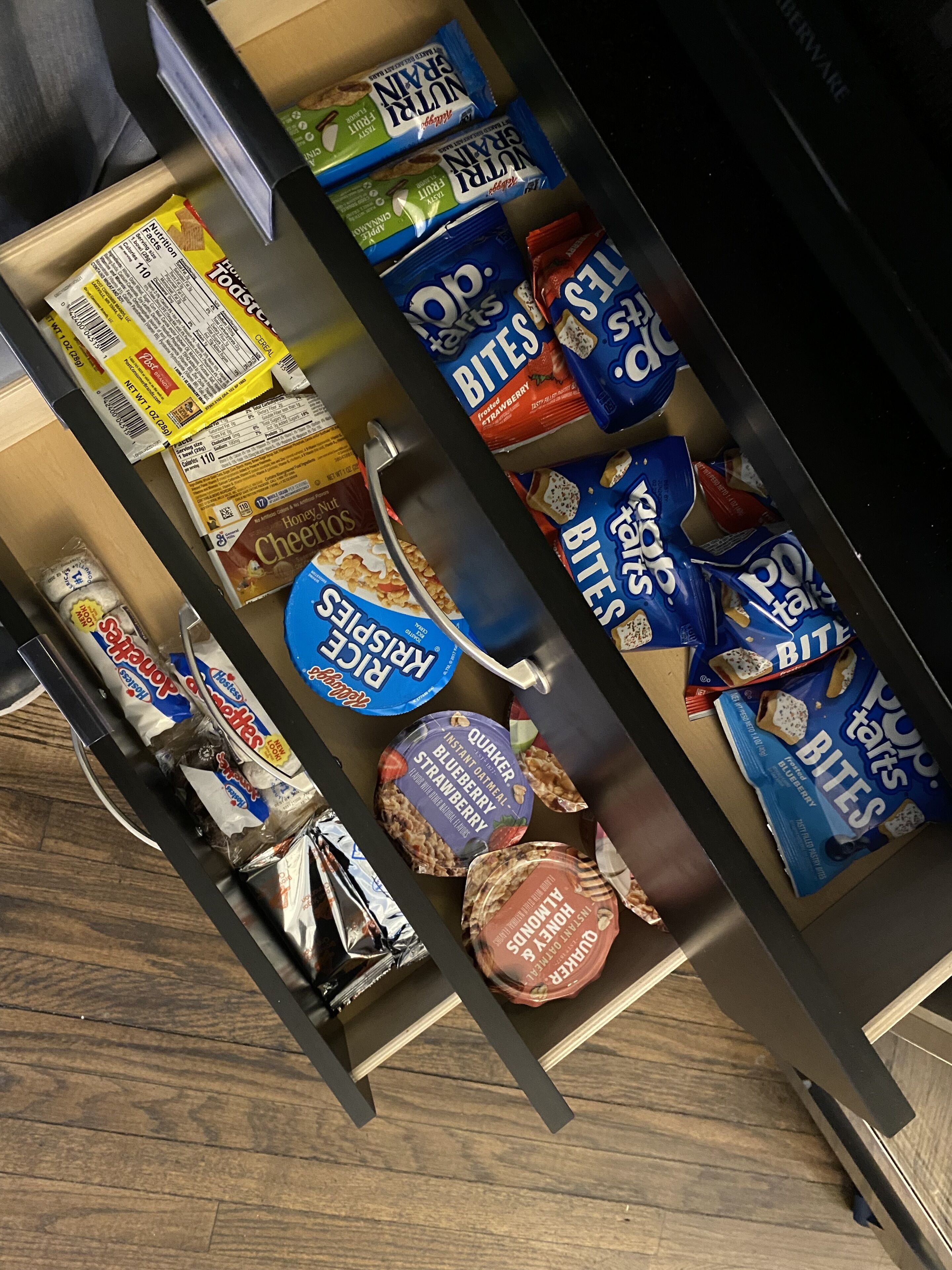 Un cajón con diversos bocadillos, incluyendo Pop Tarts, Rice Krispies y Honey Nut Cheerios.