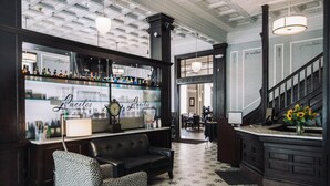 Een bar met een vloer met patroon, een leren bank en een bar waar drankflessen staan.