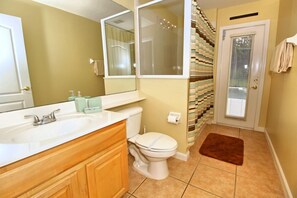 A bathroom with a white sink, wooden vanity, a toilet, and a brown rug. - 360NHD (Davenport)