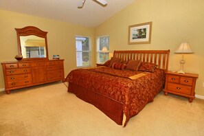 A bedroom with a large bed, a dresser, a nightstand, a lamp, and a framed picture on the wall. - 360NHD (Davenport)
