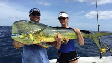 A person holding a large fish on a boat.
