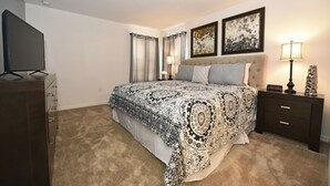 A bedroom with a large bed, two bedside tables with lamps, a TV, and a dresser. - Providence at Crofton Springs (Davenport)
