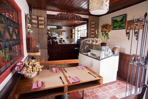 A cozy restaurant with wooden furniture, a central table with a vase of flowers, and a counter with jars. - Hotel Casa Chapultepec - Hostel (Cobán)