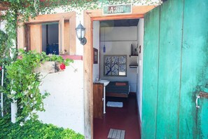 A small, rustic bathroom with a wooden door, a sink, and a window with a tree design. - Hotel Casa Chapultepec - Hostel (Cobán)