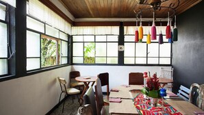 A dining area with a wooden ceiling, large windows with blinds, and a table set with a colorful table runner. - Hotel Casa Chapultepec - Hostel (Cobán)