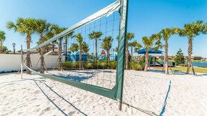 A beach volleyball net set up on a sandy area with palm trees and a clear blue sky in the background. - HOME SWEET HOME (Kissimmee)