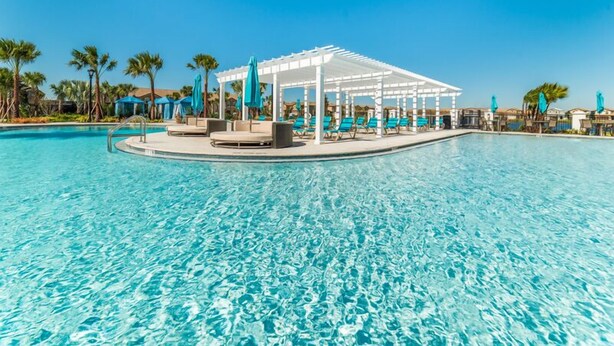 A pool area with a covered seating area and lounge chairs. - HOME SWEET HOME (Kissimmee)