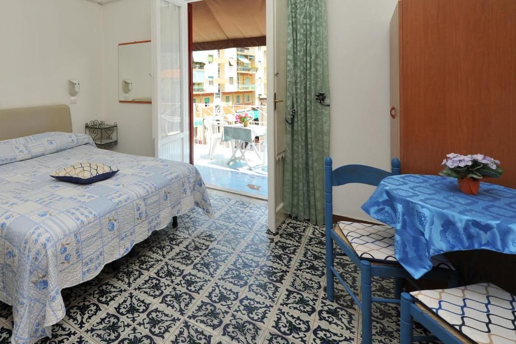 Un dormitorio con cama, una mesa con mantel, una silla y vista al balcón exterior.