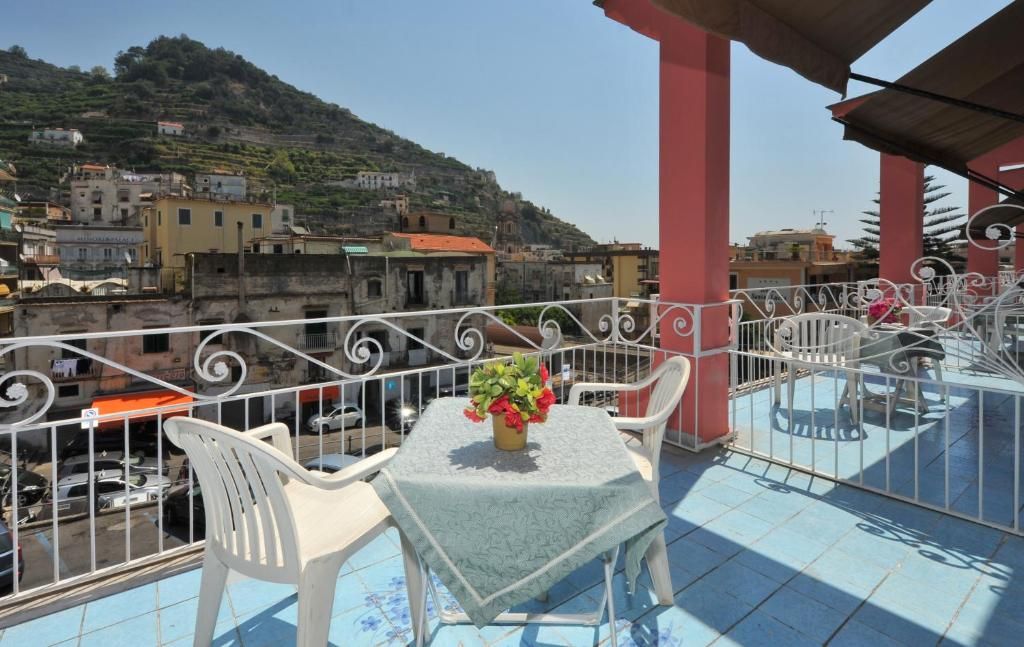Un balcon avec une table et des chaises, une balustrade et une vue sur une ville située sur une colline.