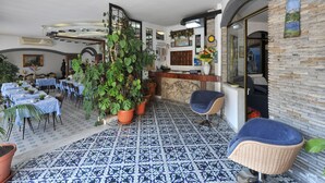 Un restaurant décoré de carreaux bleus et blancs, avec un comptoir d’accueil et plusieurs plantes en pot.