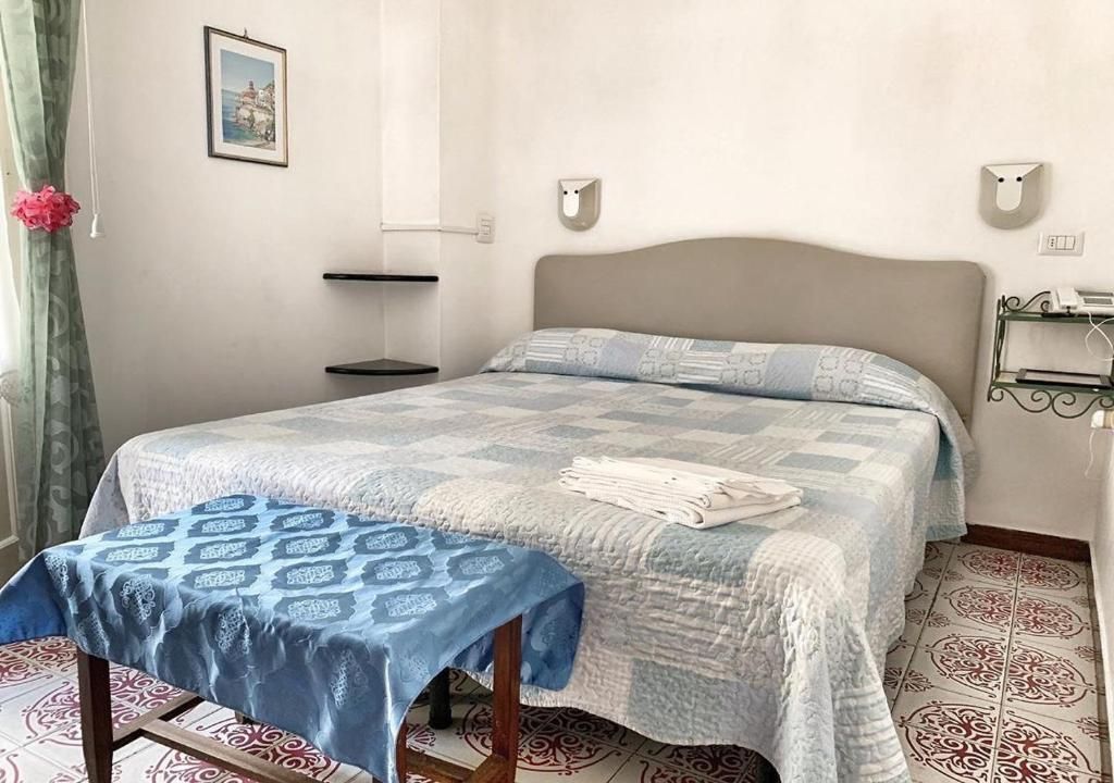 A bedroom with a bed, a bedside table, a wall-mounted shelf, and a picture on the wall.