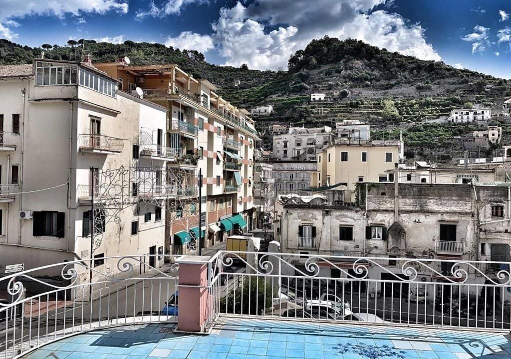 A residential area with multi-story buildings, balconies, and a hilly backdrop.