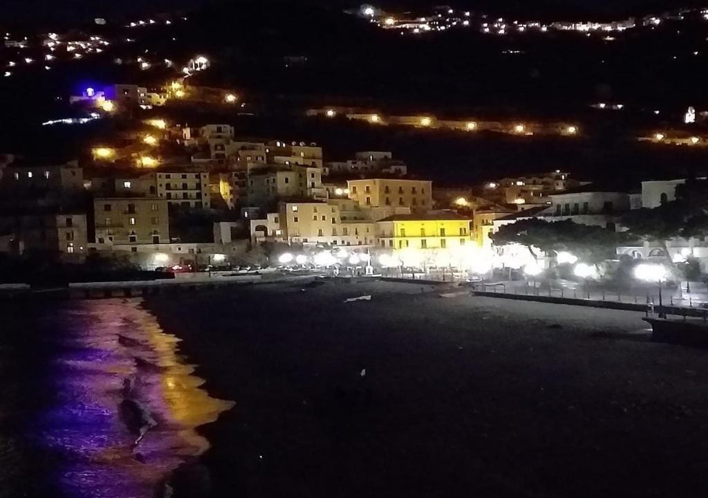 A coastal town at night with illuminated buildings and a beach.