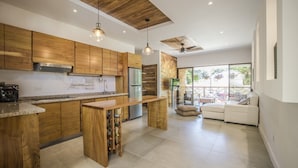 A modern kitchen with wooden cabinets, a central island, and a built-in wine rack. - Umami Hotel - Adults Only (Cahuita)