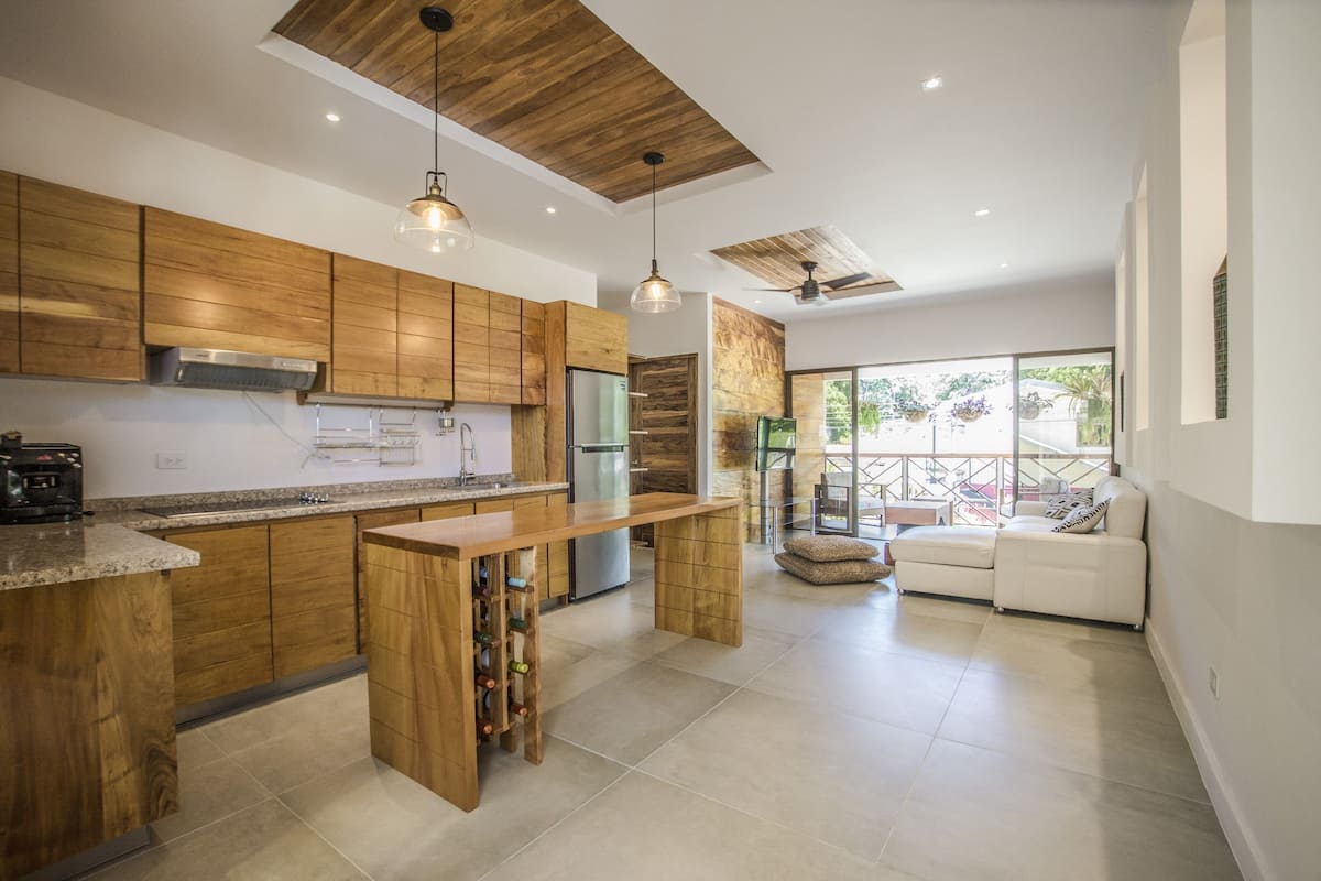 A modern kitchen with wooden cabinets, a central island, and a built-in wine rack.