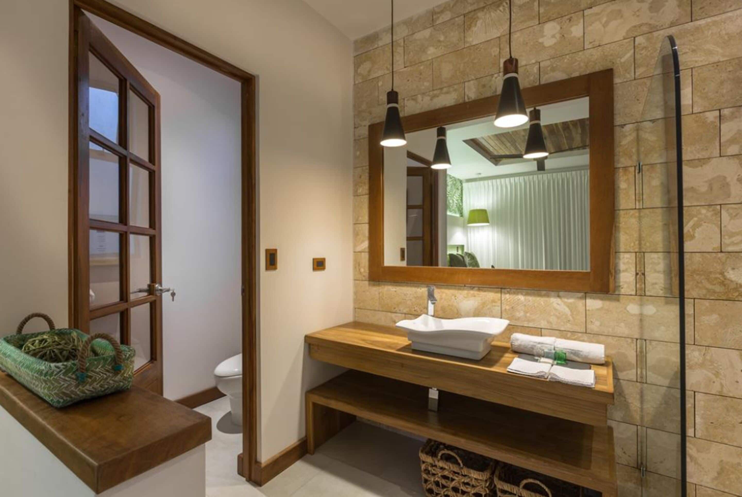 A bathroom with a wooden vanity, a large mirror, and pendant lighting.