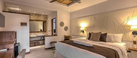 Un dormitorio moderno con una cama grande, techo de madera, escritorio empotrado y un baño con pared de piedra.