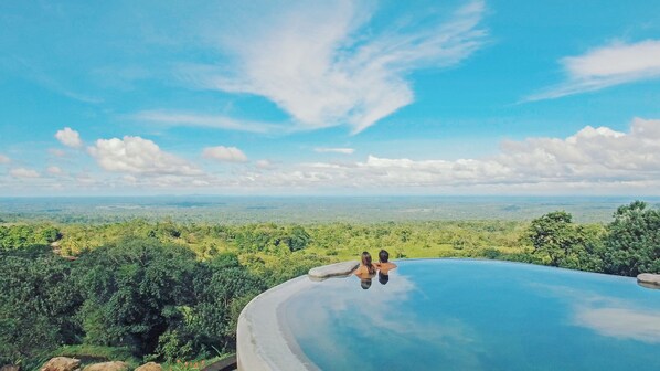 A large, clear infinity pool with a view of a dense forest and distant horizon. - Origins Lodge (Bijagua)