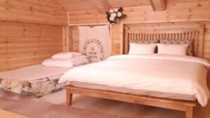 Een houten kamer met een bed en een klein zithoekje.