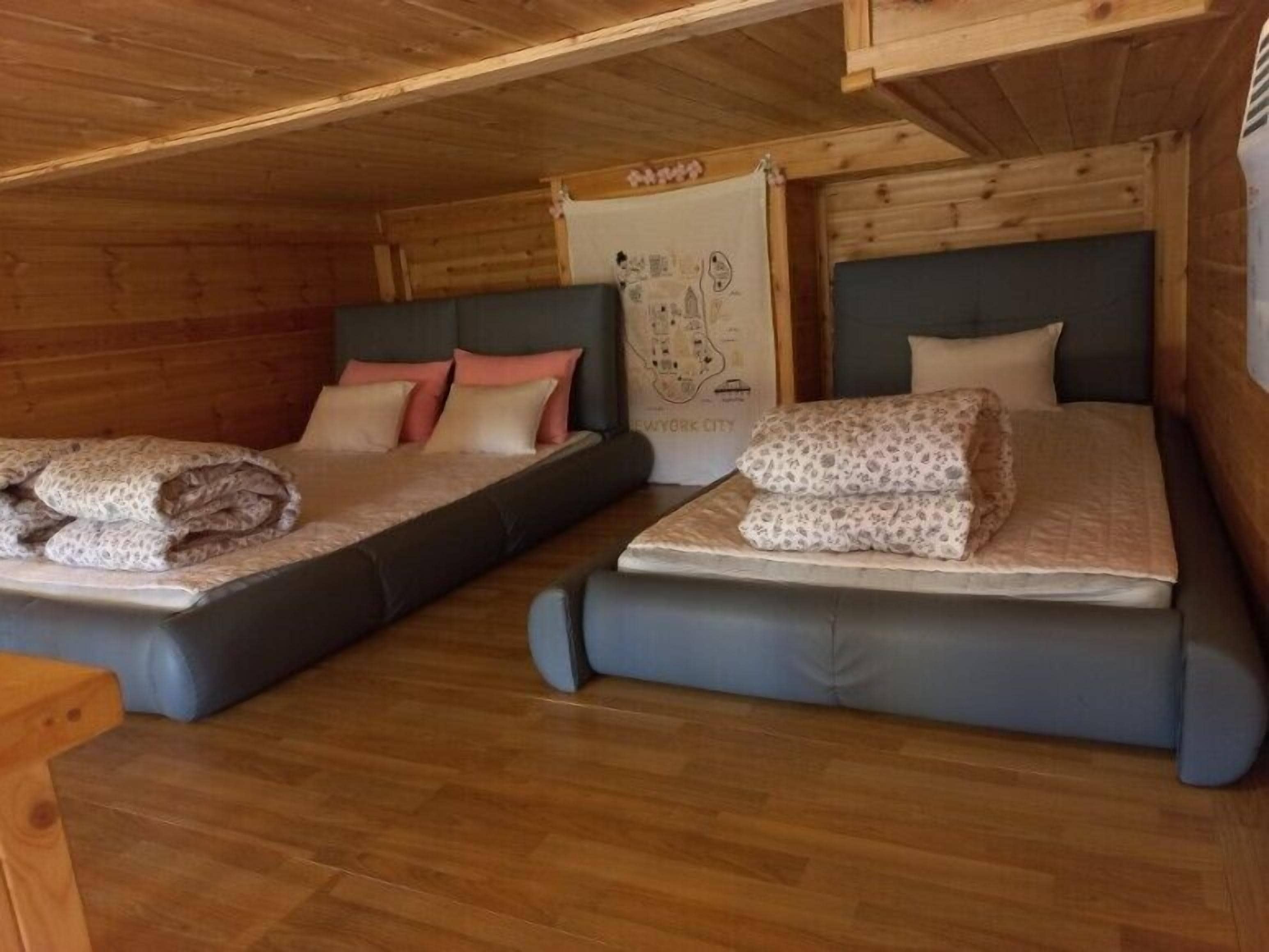 A cabin-style room with two beds, wooden walls, and a map on the wall.