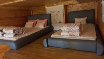 A cabin-style room with two beds, wooden walls, and a map on the wall.