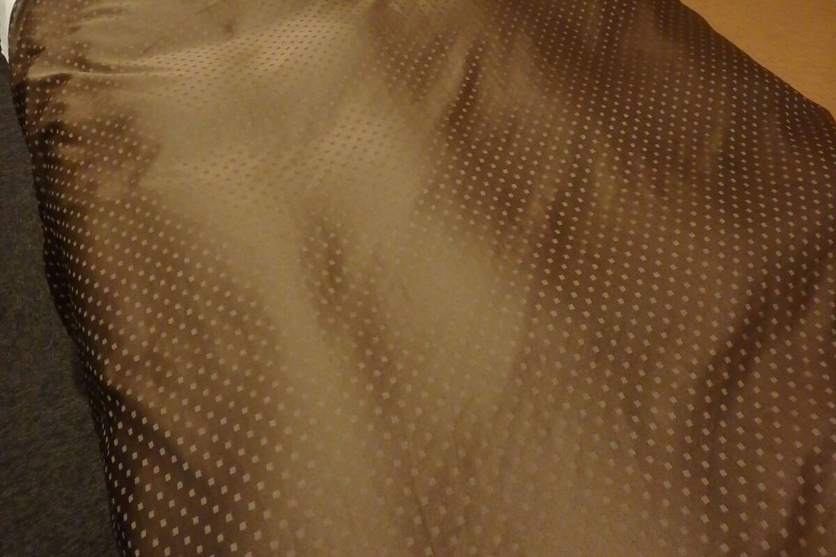 Un lit avec une couverture à motifs marron, un oreiller blanc et une tête de lit en bois.