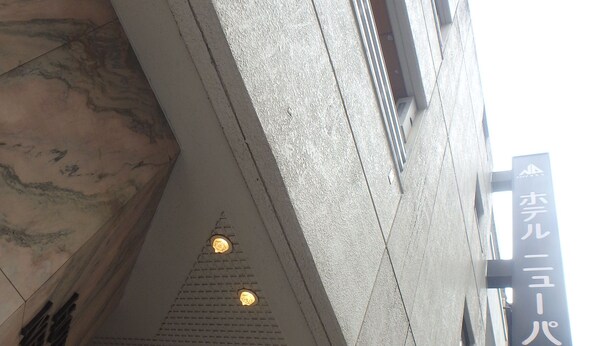 A building with a stone facade, a sign with Japanese characters, and a series of recessed lights on the upper floor. - Hotel New Park (Tokyo)