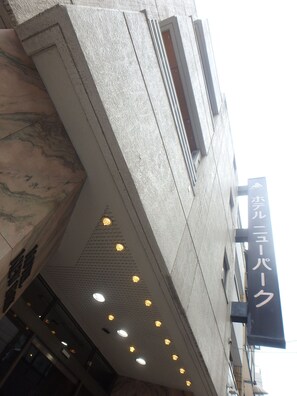 A building with a stone facade, a sign with Japanese characters, and a series of recessed lights on the upper floor. - Hotel New Park (Tokyo)