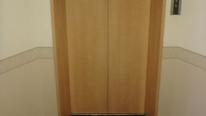 A closed elevator door with a control panel on the wall. - Hotel New Park (Tokyo)