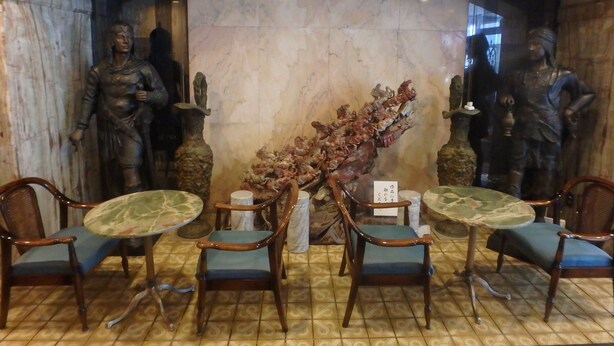 A dining area with marble walls, two statues, and four wooden chairs with blue cushions. - Hotel SUNTARGAS UENO (Tokyo)