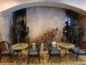 A dining area with marble walls, two statues, and four wooden chairs with blue cushions. - Hotel SUNTARGAS UENO (Tokyo)