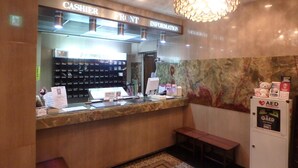 A hotel reception area with a marble counter, a cashier front desk, an AED emergency station, and a chandelier. - Hotel SUNTARGAS UENO (Tokyo)